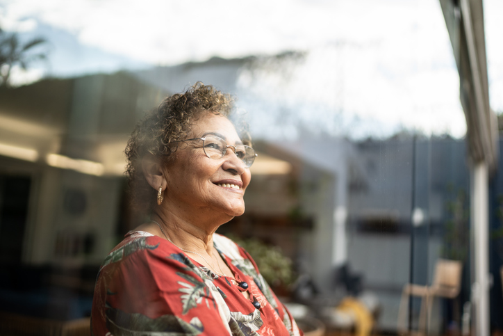 Senior woman smiling and looking out of window at home