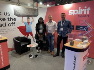 Three people posing in front of event stand 