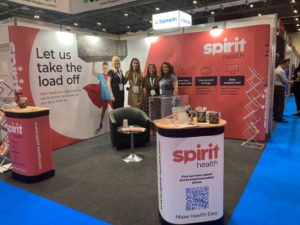 Four women posing for photo in front of event stand