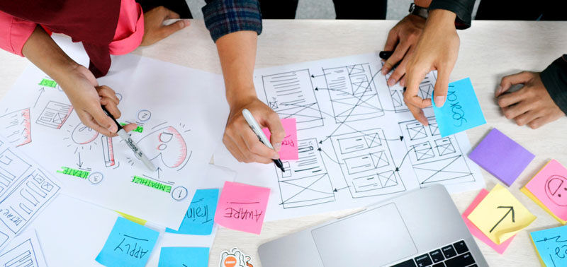 A top down view of people planning with post-it notes and wireframes