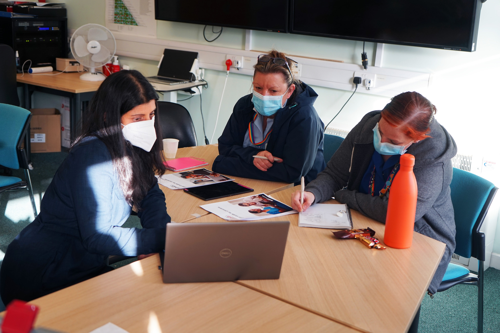 Three people sat round a computer, looking at training materials