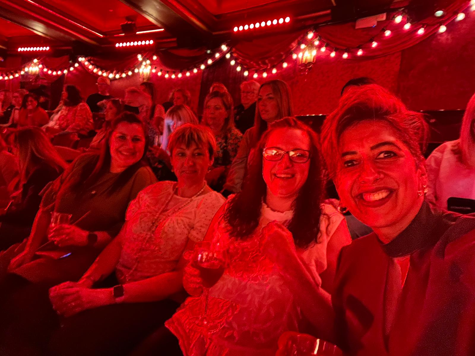 Group of people smiling in the audience of a theatre in London