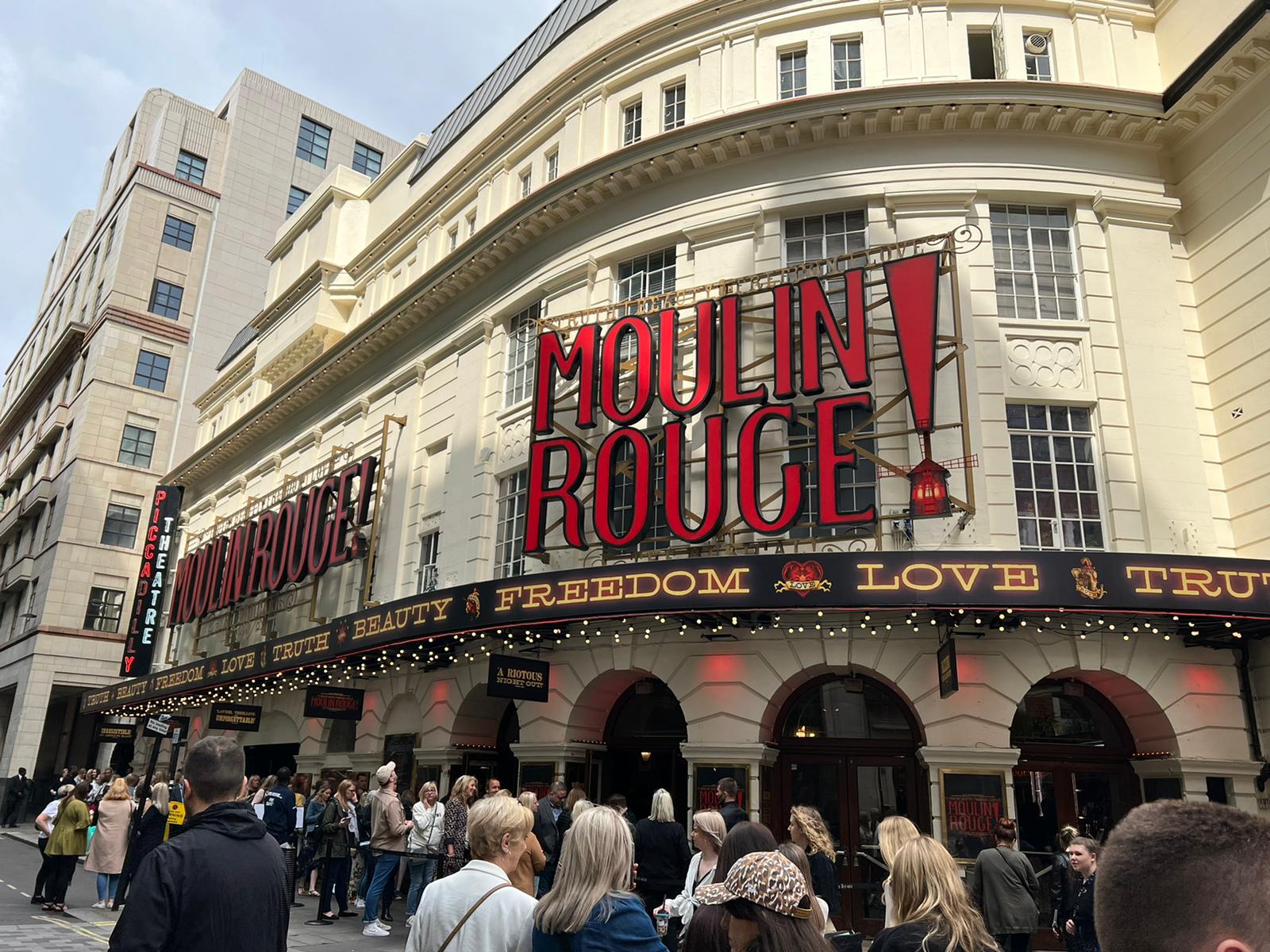 Outside of a theatre in London with a sign for Moulin Rouge