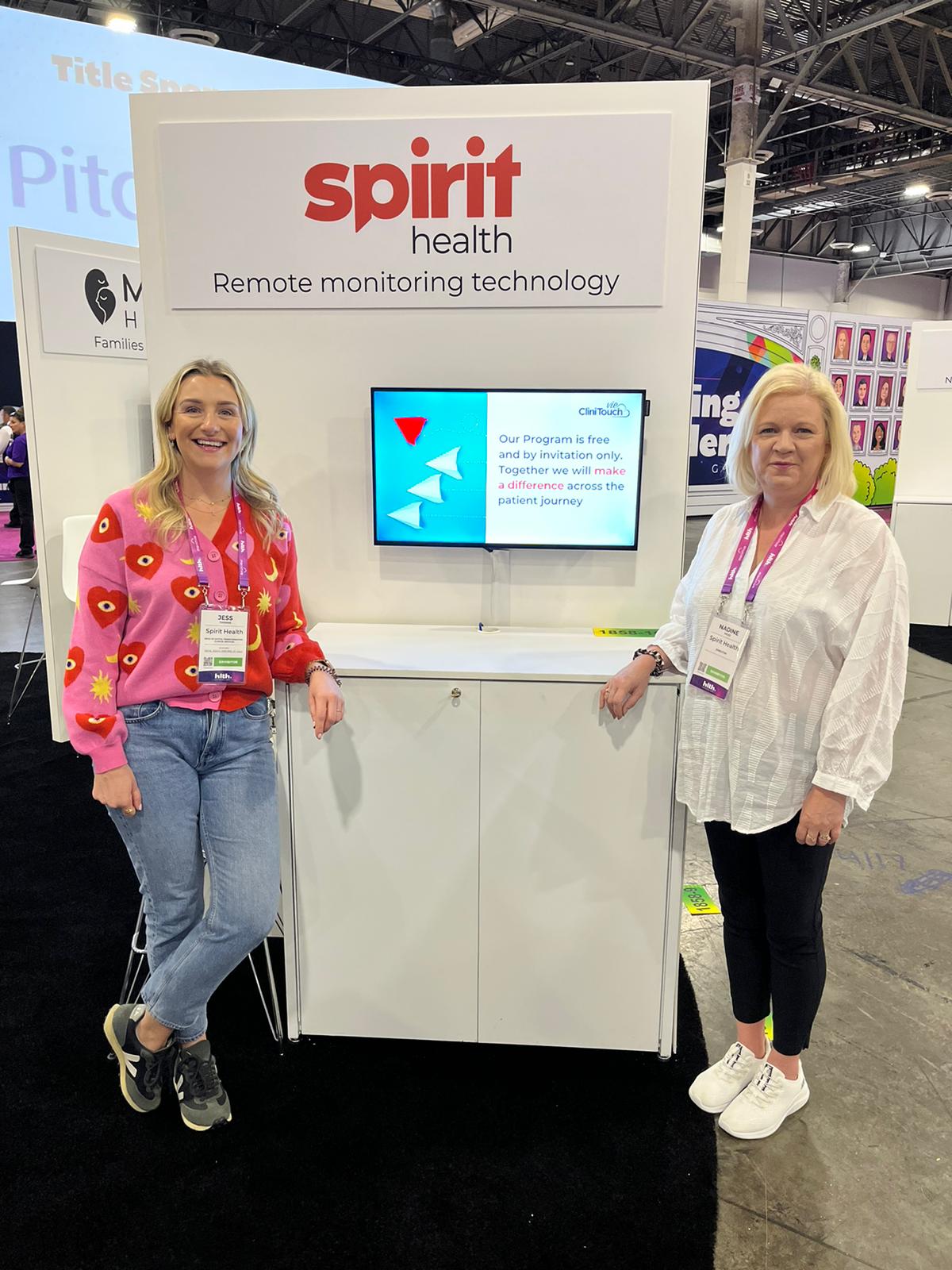 Two women stood either side of a podium for 'Spirit Health'. Both smiling