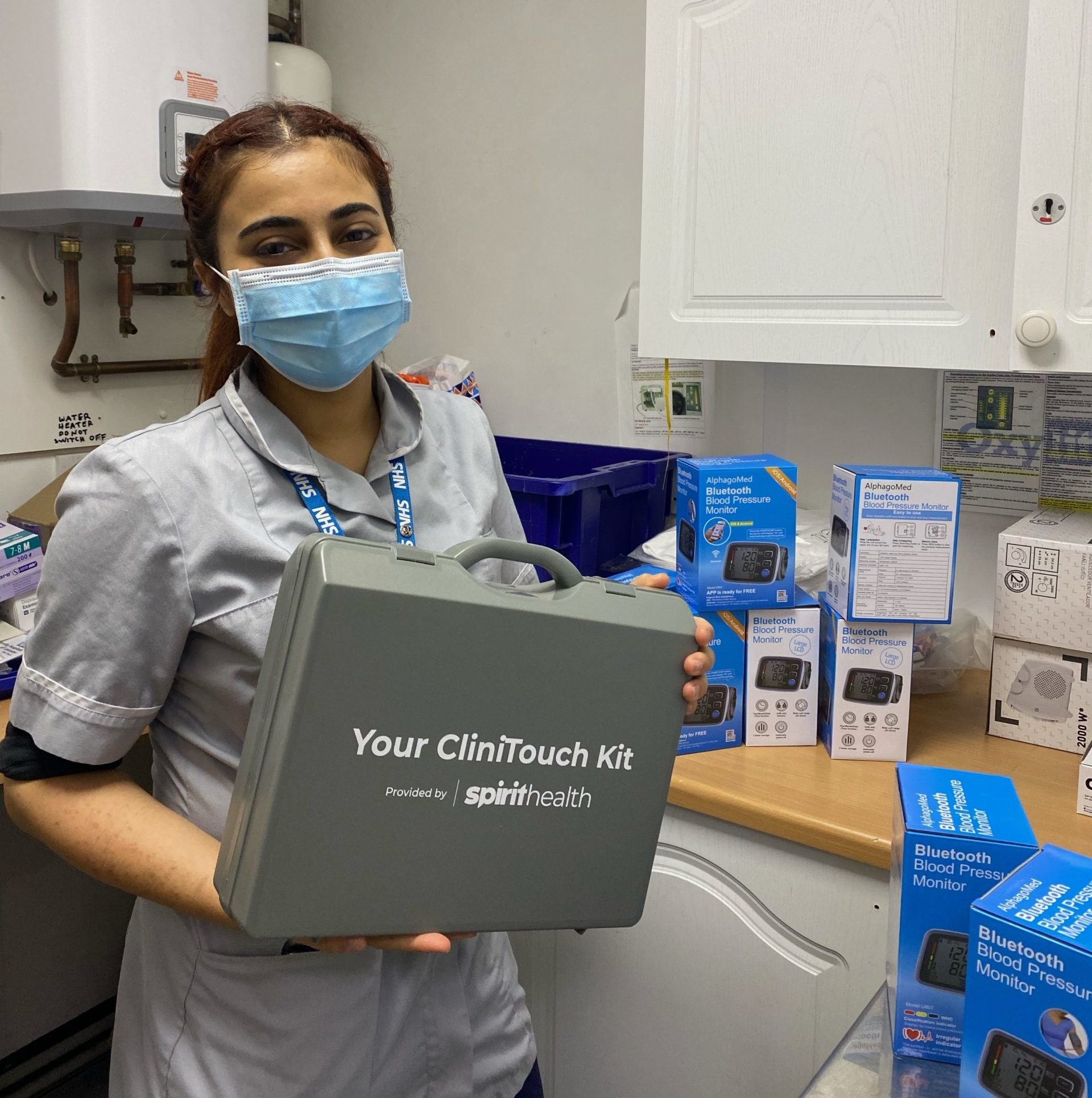 Woman in face mask and clinical clothes. She is holding a box of supplies