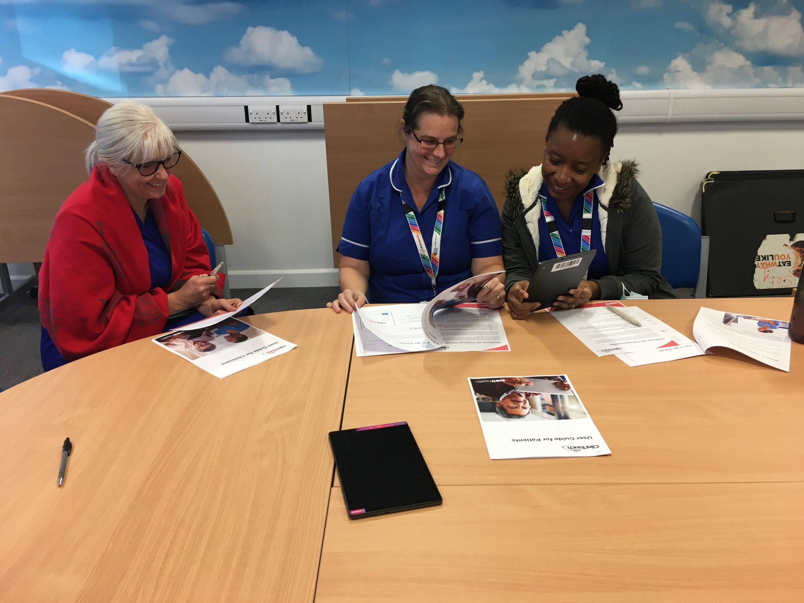 Three nurses sat at a table reviewing Clinitouch documents